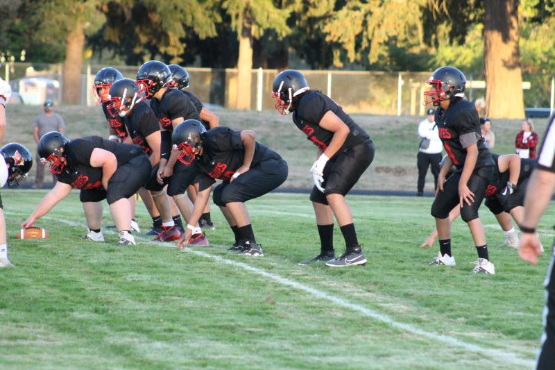 A group of student football players wearing black and red uniforms, ready to play on the field.