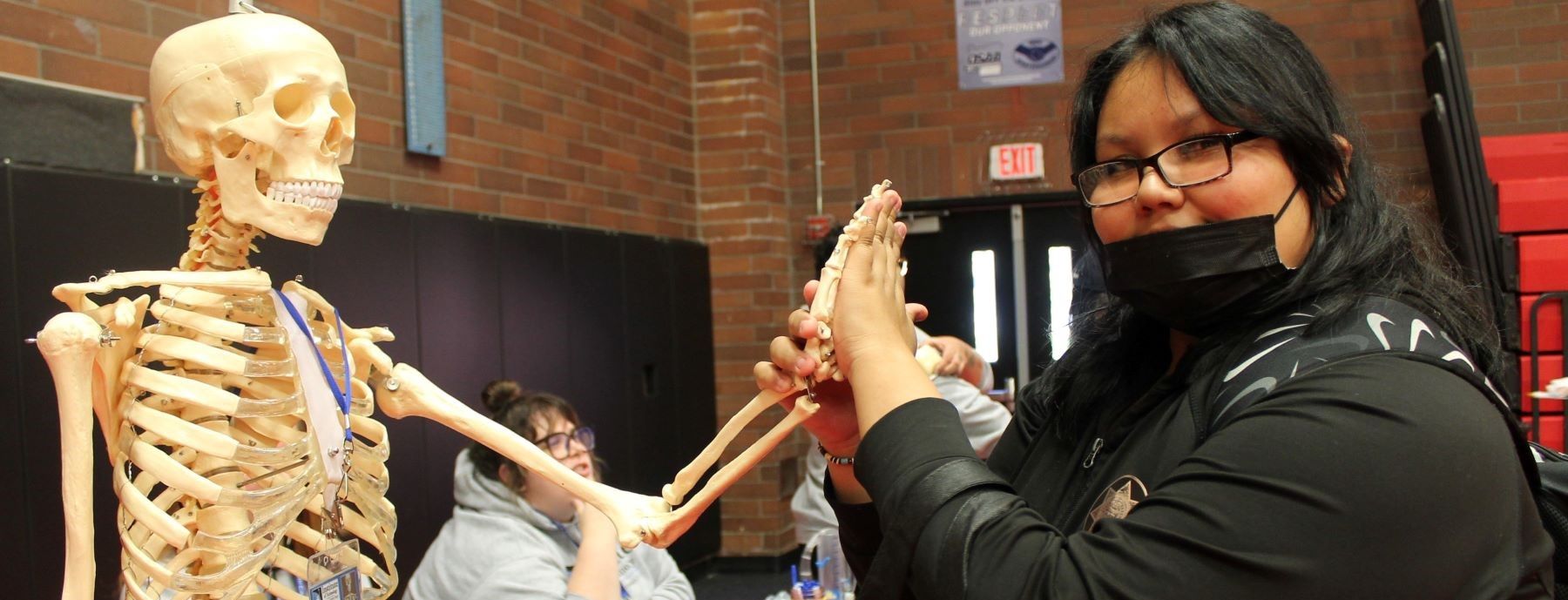 Student high-fiving a medical skeleton.