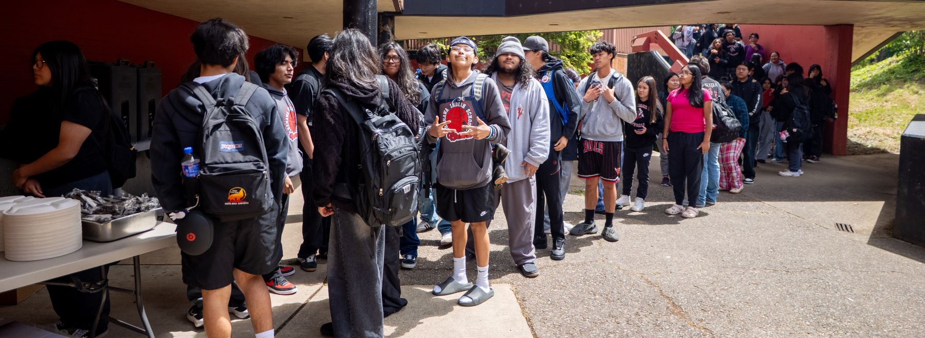 Students standing outside in line at school, eagerly waiting to receive their meals.
