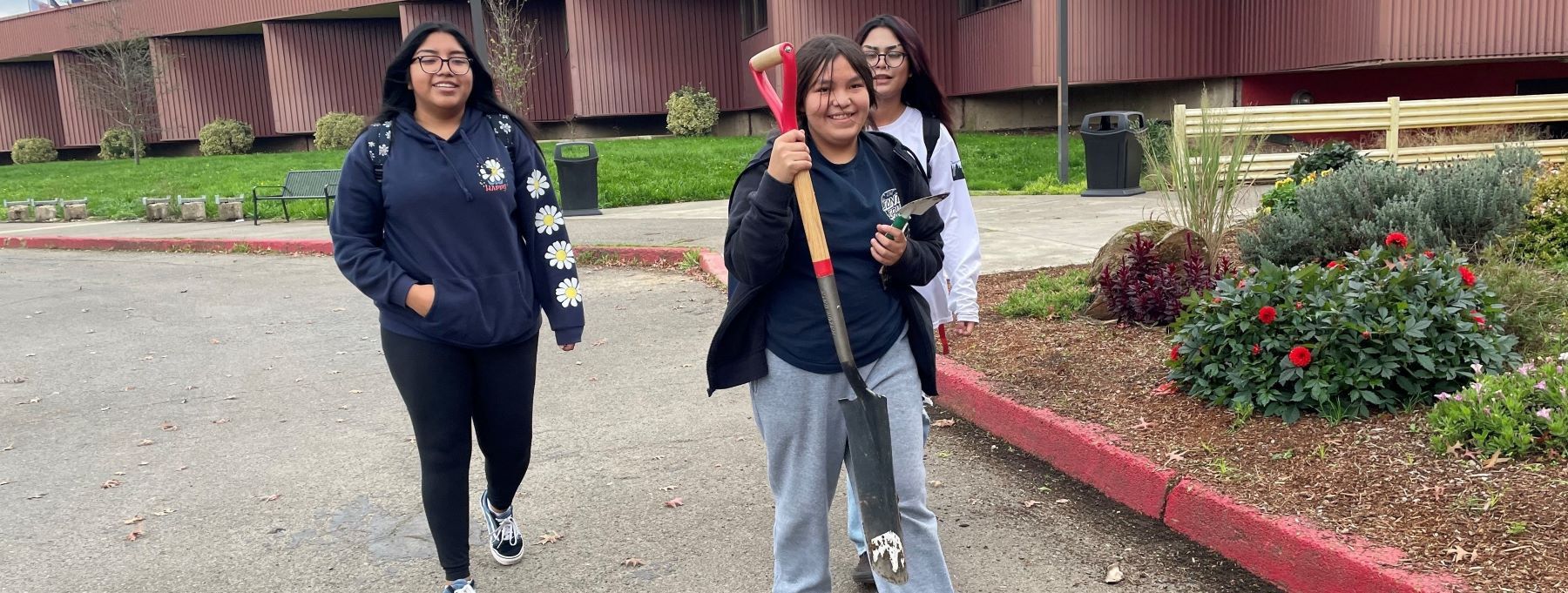 Three smiling students walking together outside.