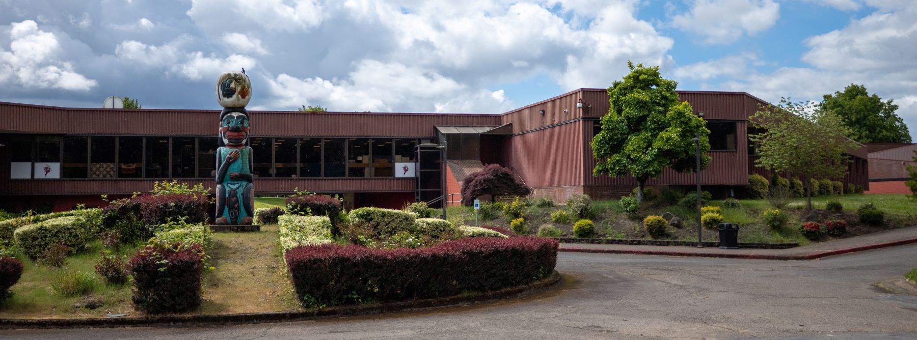 Chemawa school building with a colorful totem pole standing in front of it.
