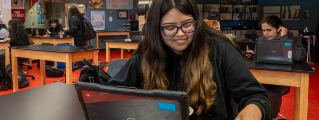 Students working on laptops in classroom.